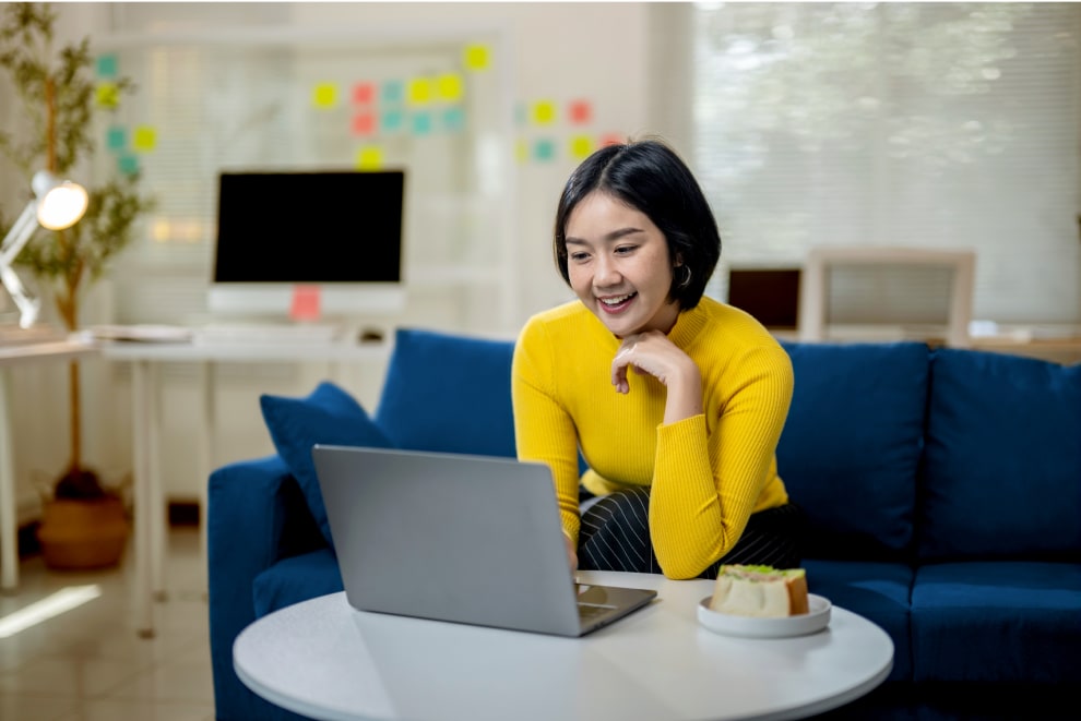 Woman smiling while using a laptop and earning electricity bill credits